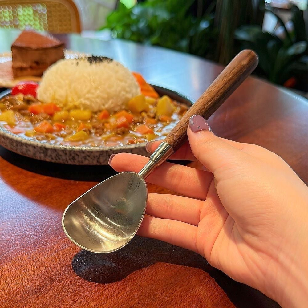 304 stainless steel watermelon baller spoon with a walnut-style handle, shown scooping melon beside a fruit bowl.