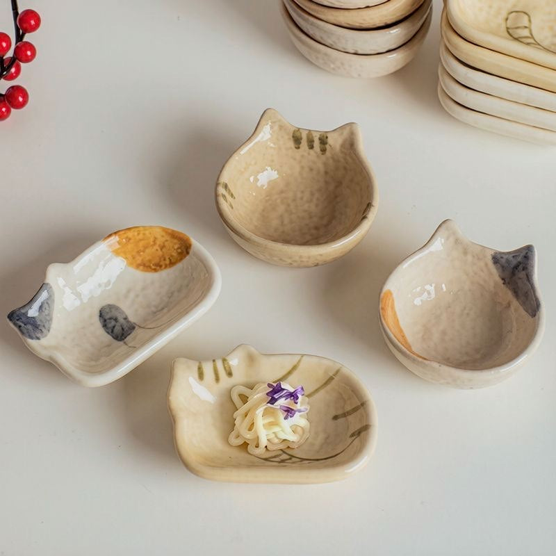 Cat-shaped ceramic dishes arranged for serving, with one shallow dish holding a small noodle serving.