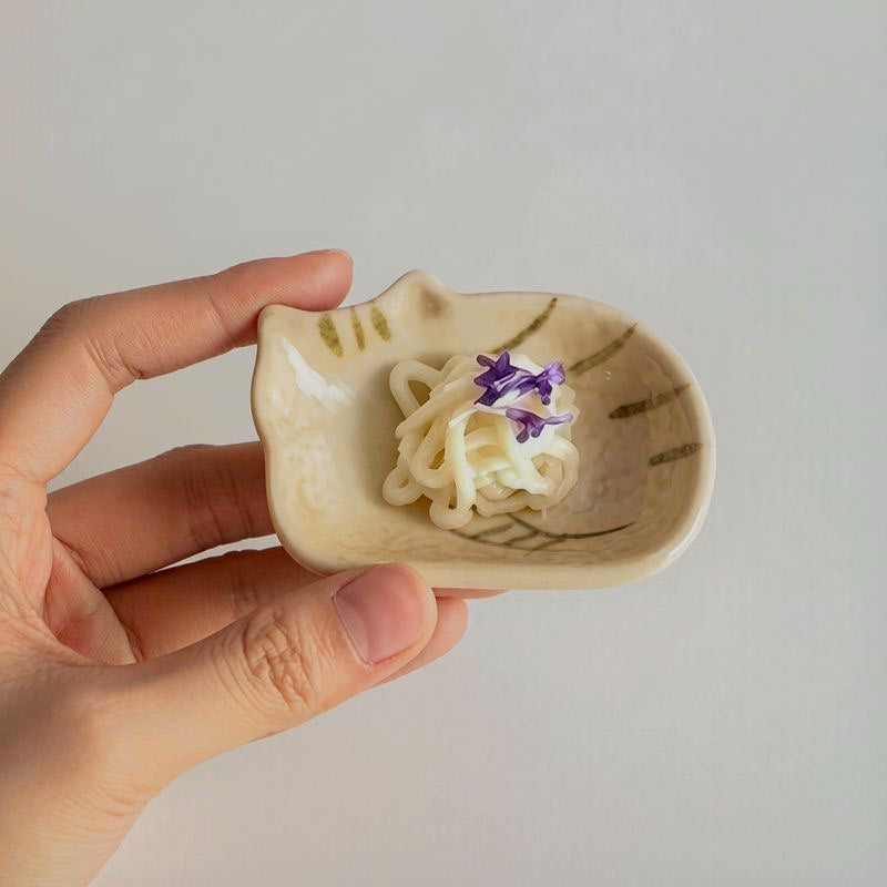 Single cat-shaped ceramic dish held in hand with a small noodle serving.
