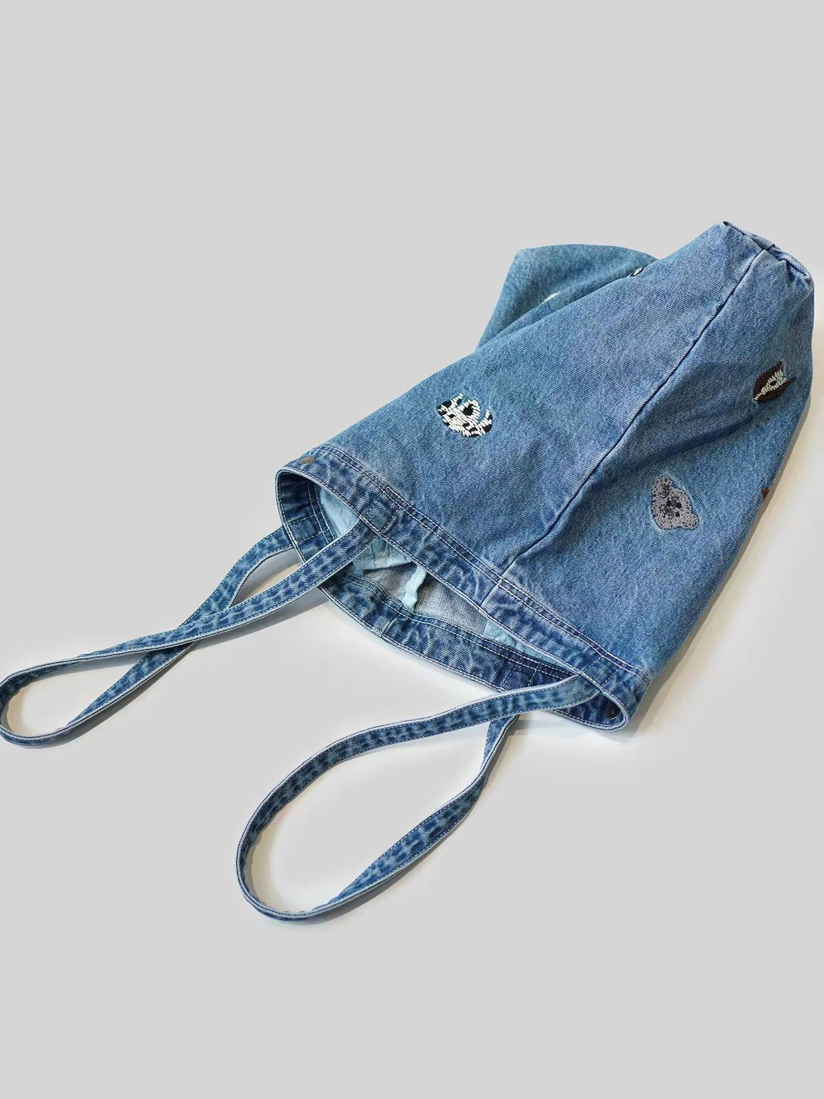 Washed-blue embroidered denim tote photographed with its long shoulder straps