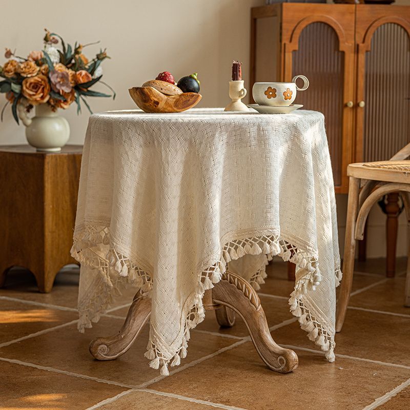 Beige tasseled tablecloth styled on a round side table