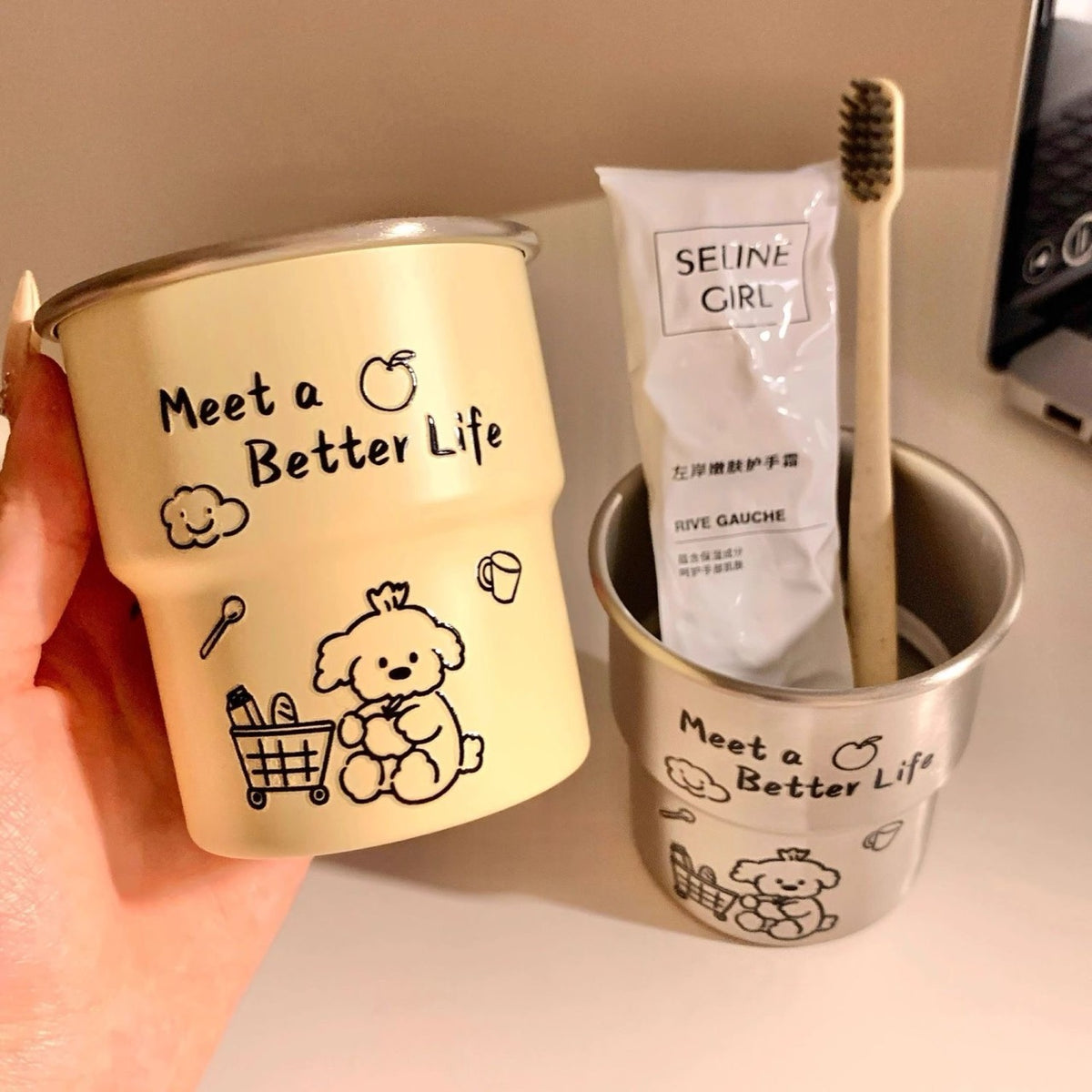 Hand holding the ivory and silver tiered toothbrush cups side by side.